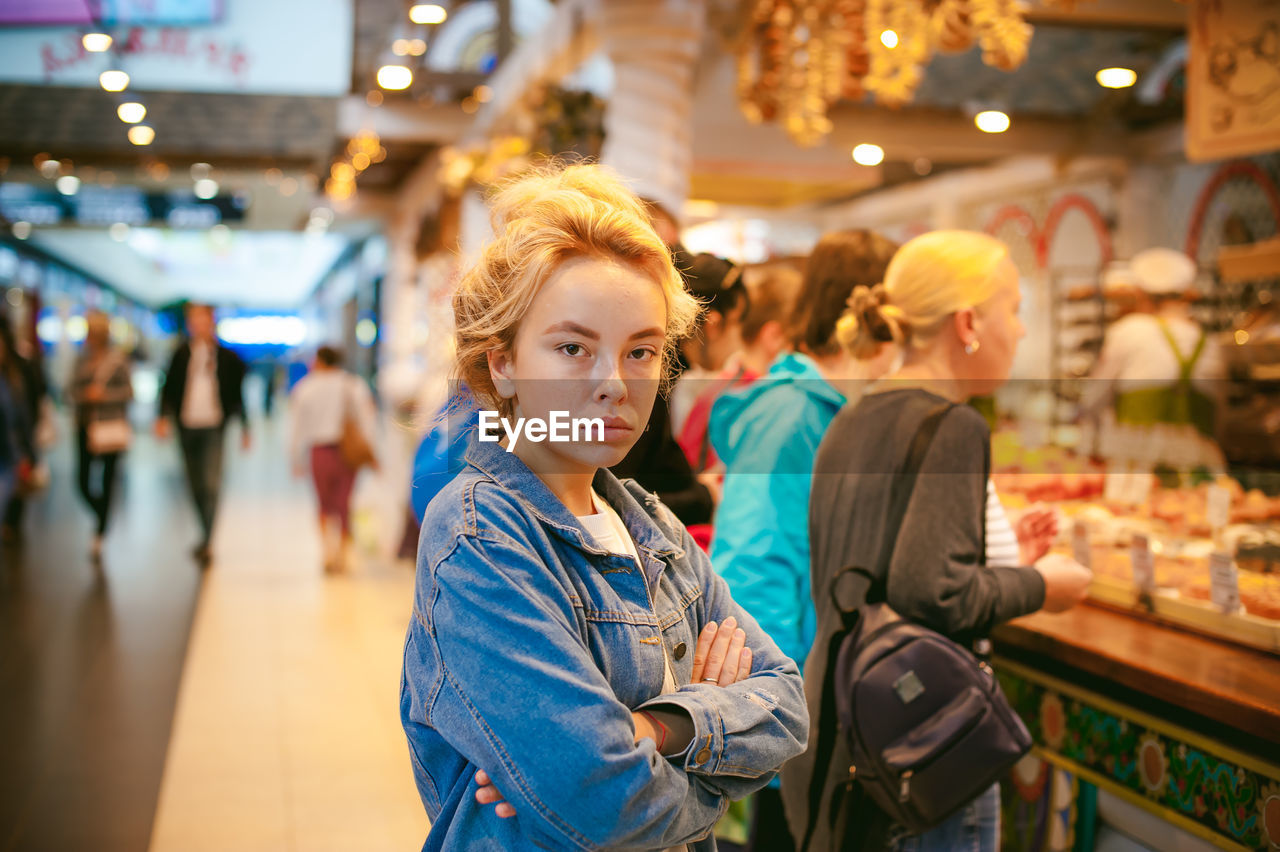 Portrait of young woman standing in illuminated market