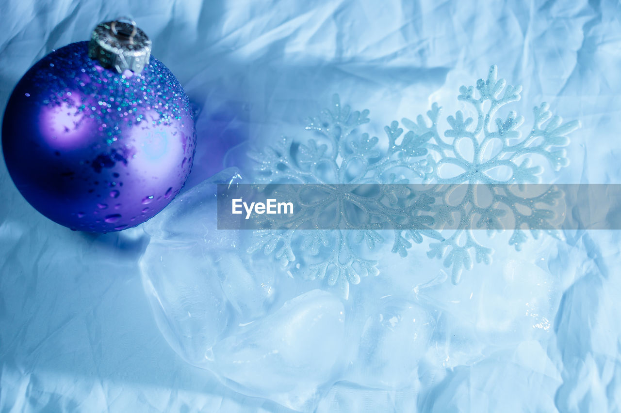 Close-up of blue christmas decoration by snowflakes and ice