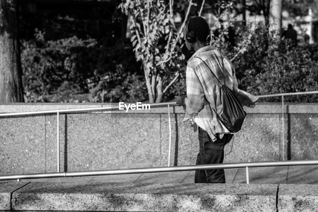 REAR VIEW OF MAN WITH UMBRELLA AGAINST TREES