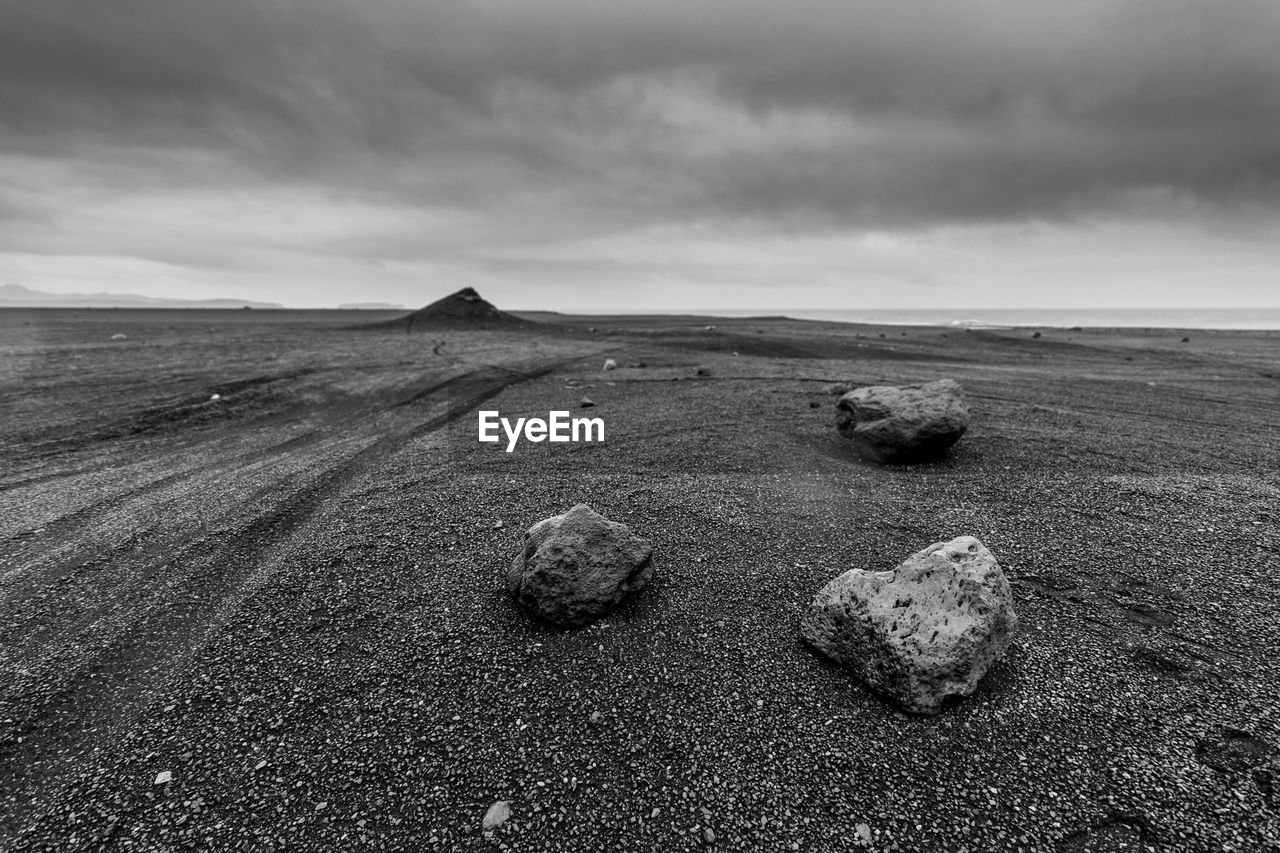 Rocks at beach against cloudy sky