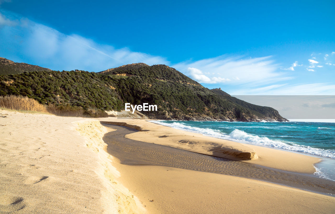 River flows through sand to the sea at solanas beach in sardinia italy