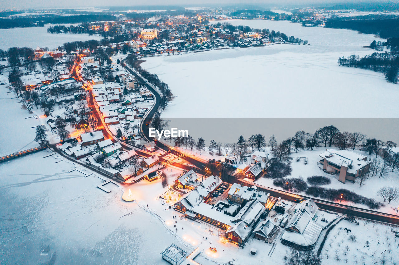 HIGH ANGLE VIEW OF FROZEN RIVER AMIDST BUILDINGS DURING WINTER