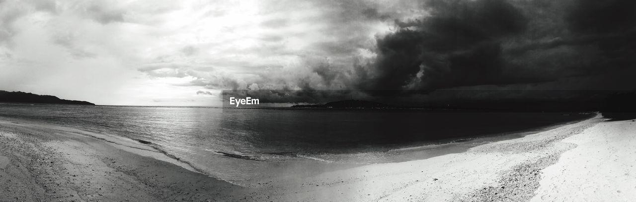 PANORAMIC VIEW OF BEACH AGAINST STORM CLOUDS