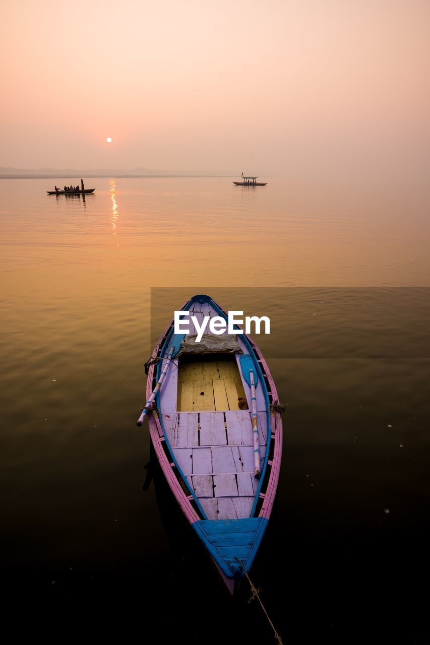 Boat in sea against sky during sunset