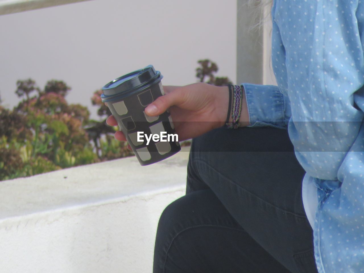 Midsection of woman photographing with coffee cup