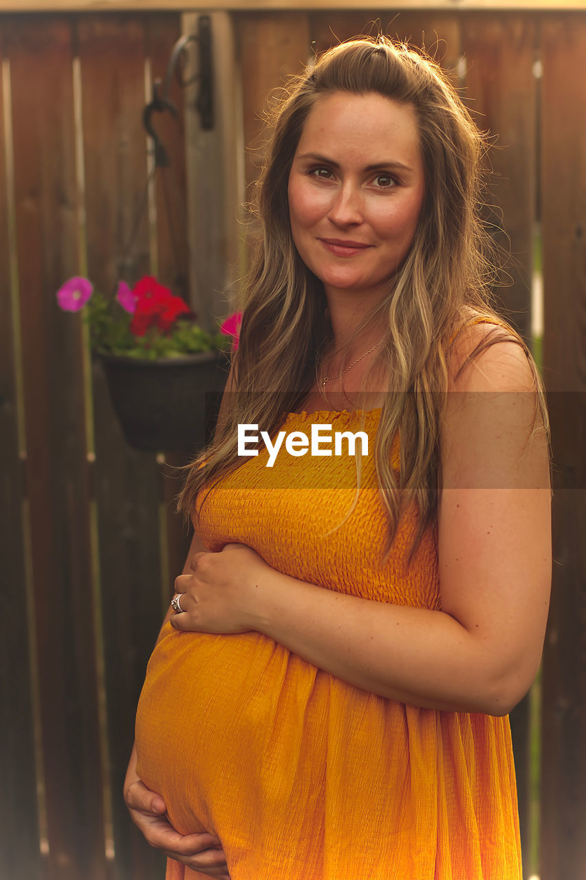 Portrait of smiling pregnant woman standing in yard