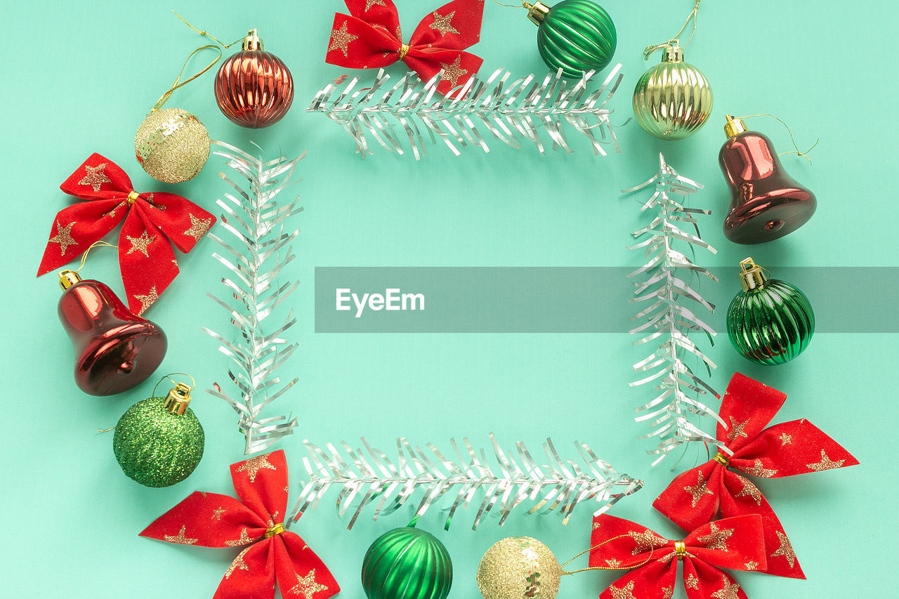 Christmas decoration of baubles bows bells on mint paper with copy space silver tree frame.