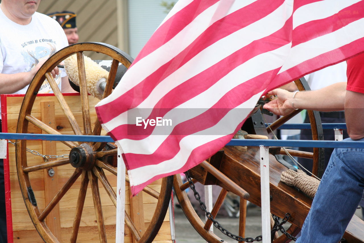 Men by cannon and american flag on street during fourth of july parade