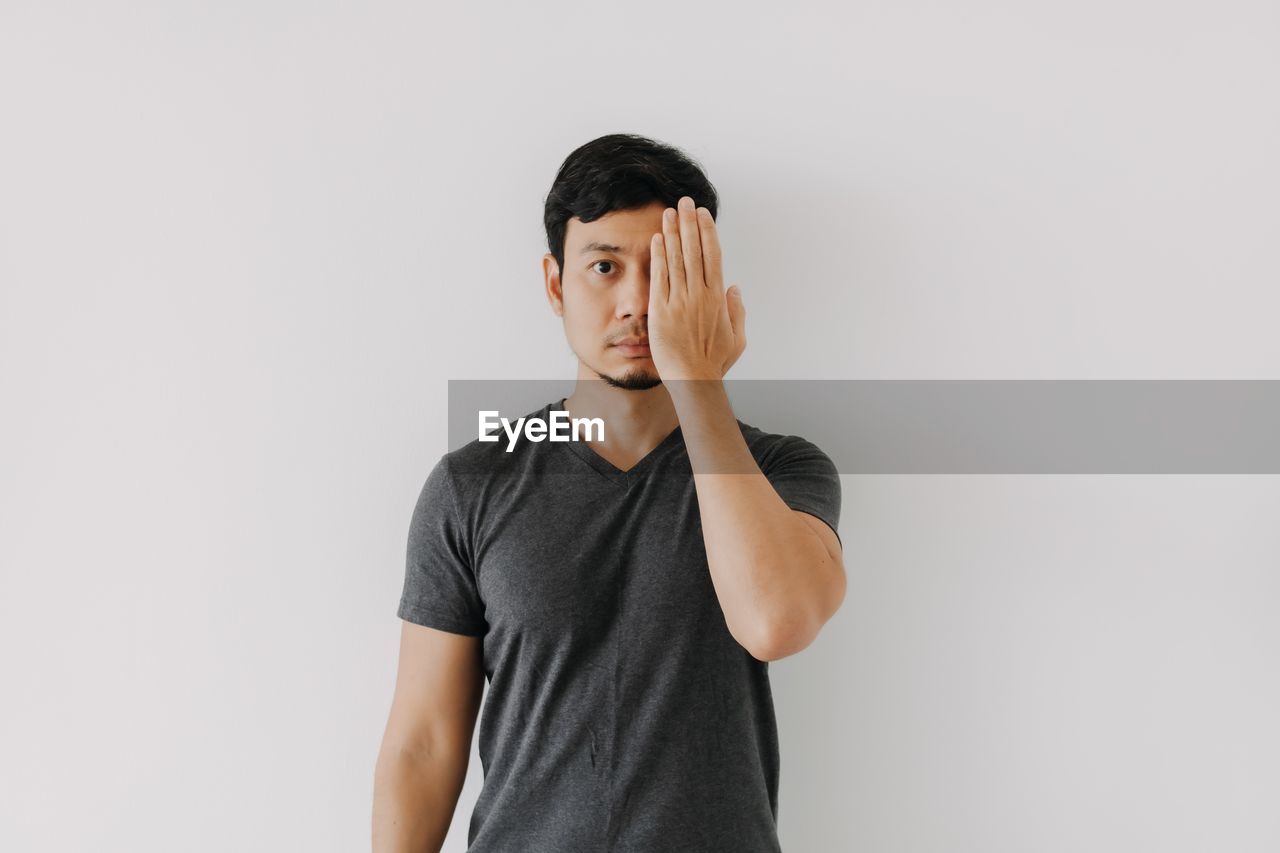 portrait of young man standing against gray background