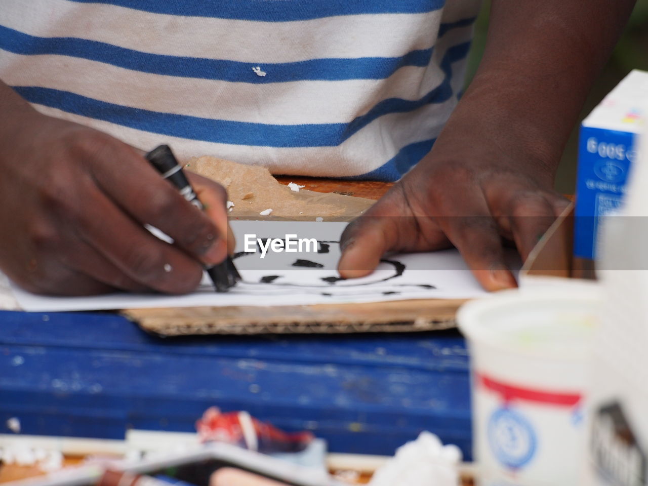 Close-up of man drawing with crayon on paper