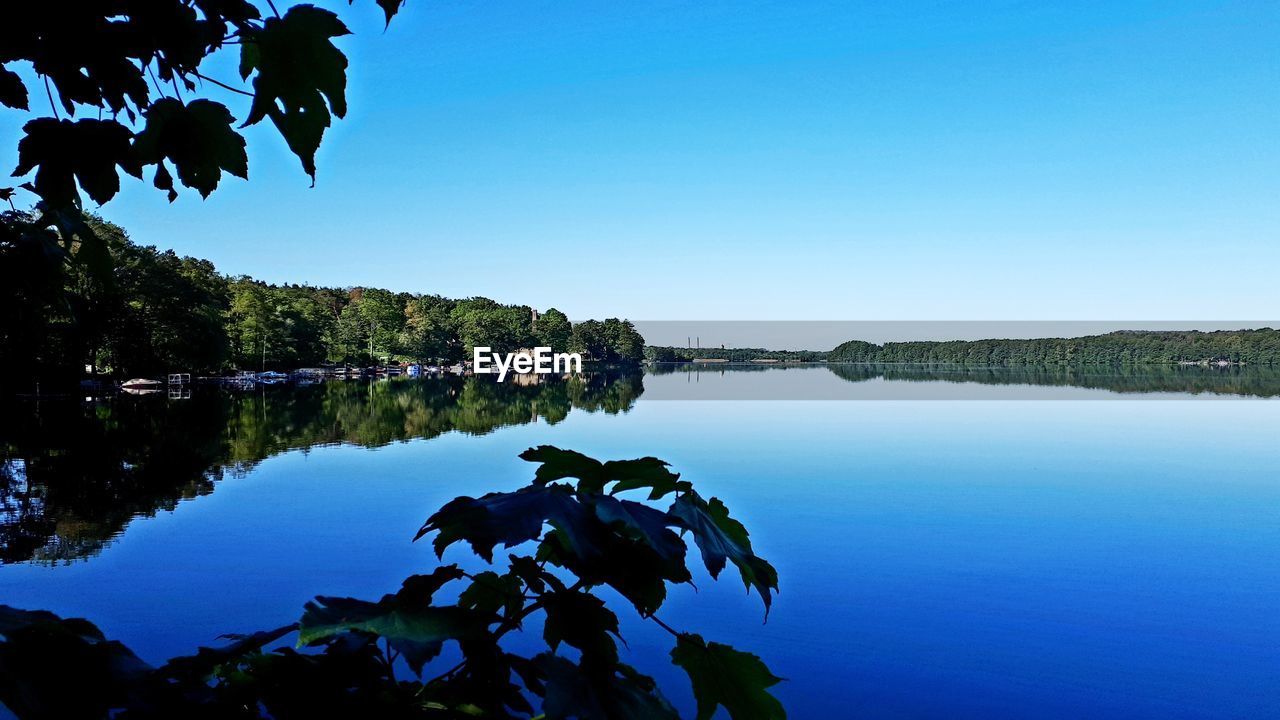 Scenic view of lake against clear blue sky