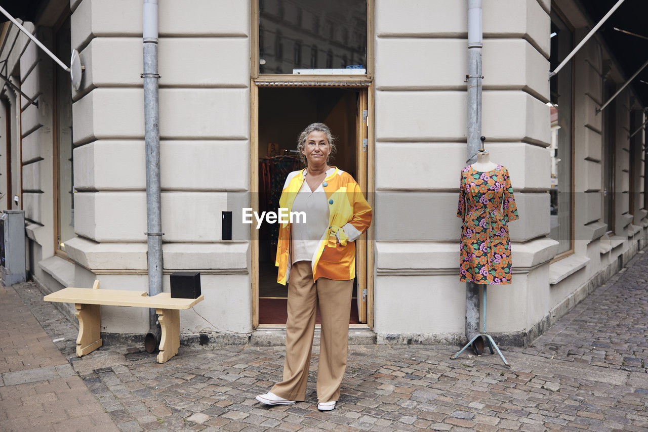 Portrait of female owner with disability standing in front of store