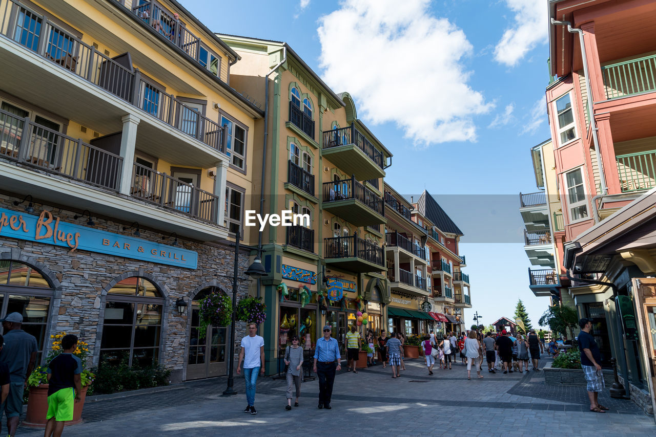 PEOPLE WALKING ON STREET BY BUILDINGS IN CITY