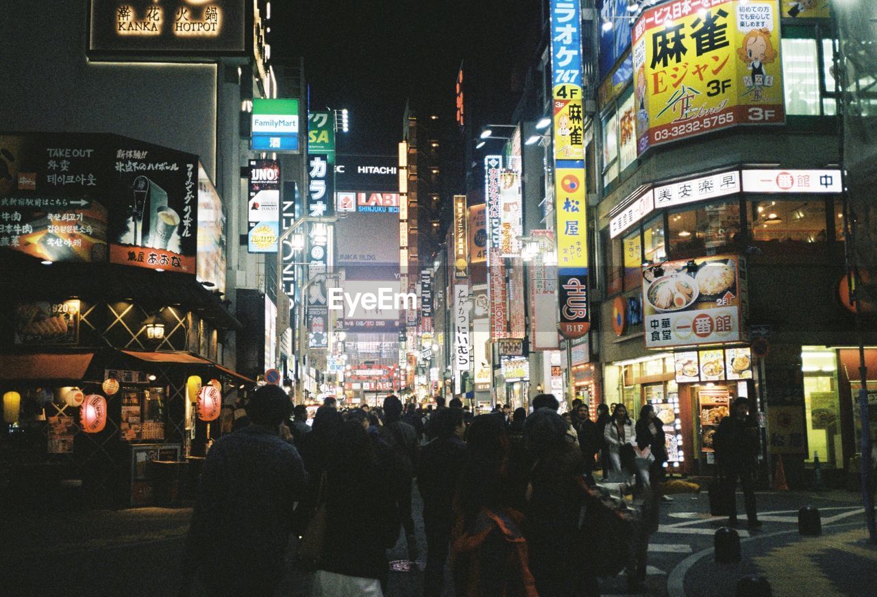 People walking on illuminated street in tokyo