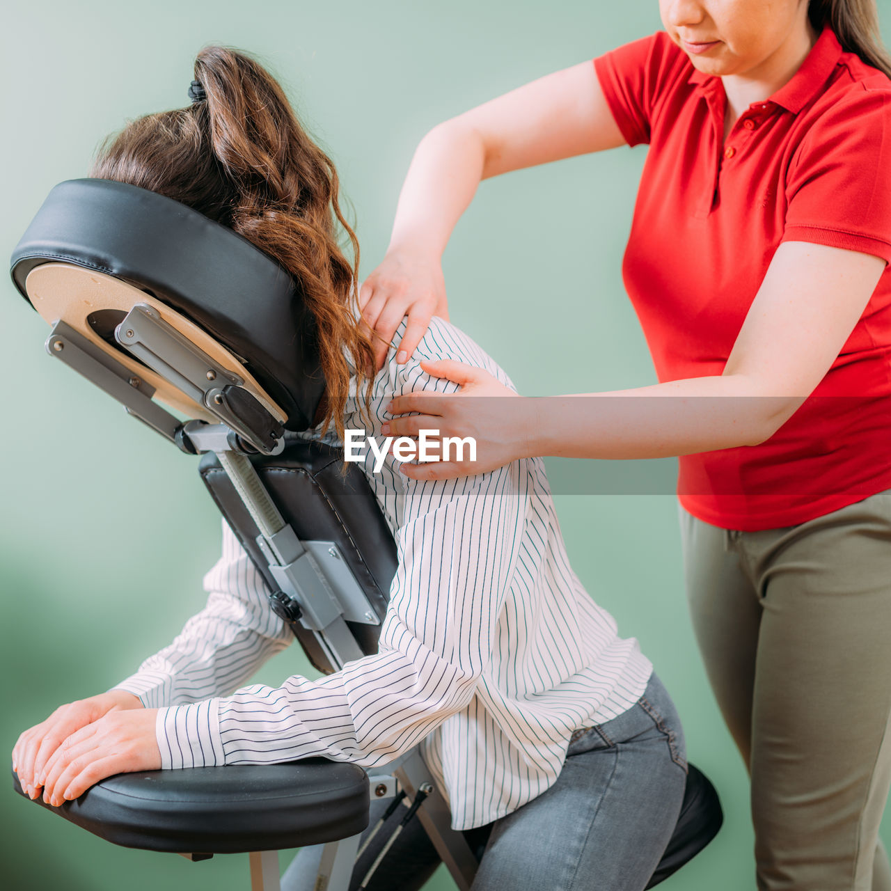 Female employee sitting on a portable massage chair in business office. therapist massaging 