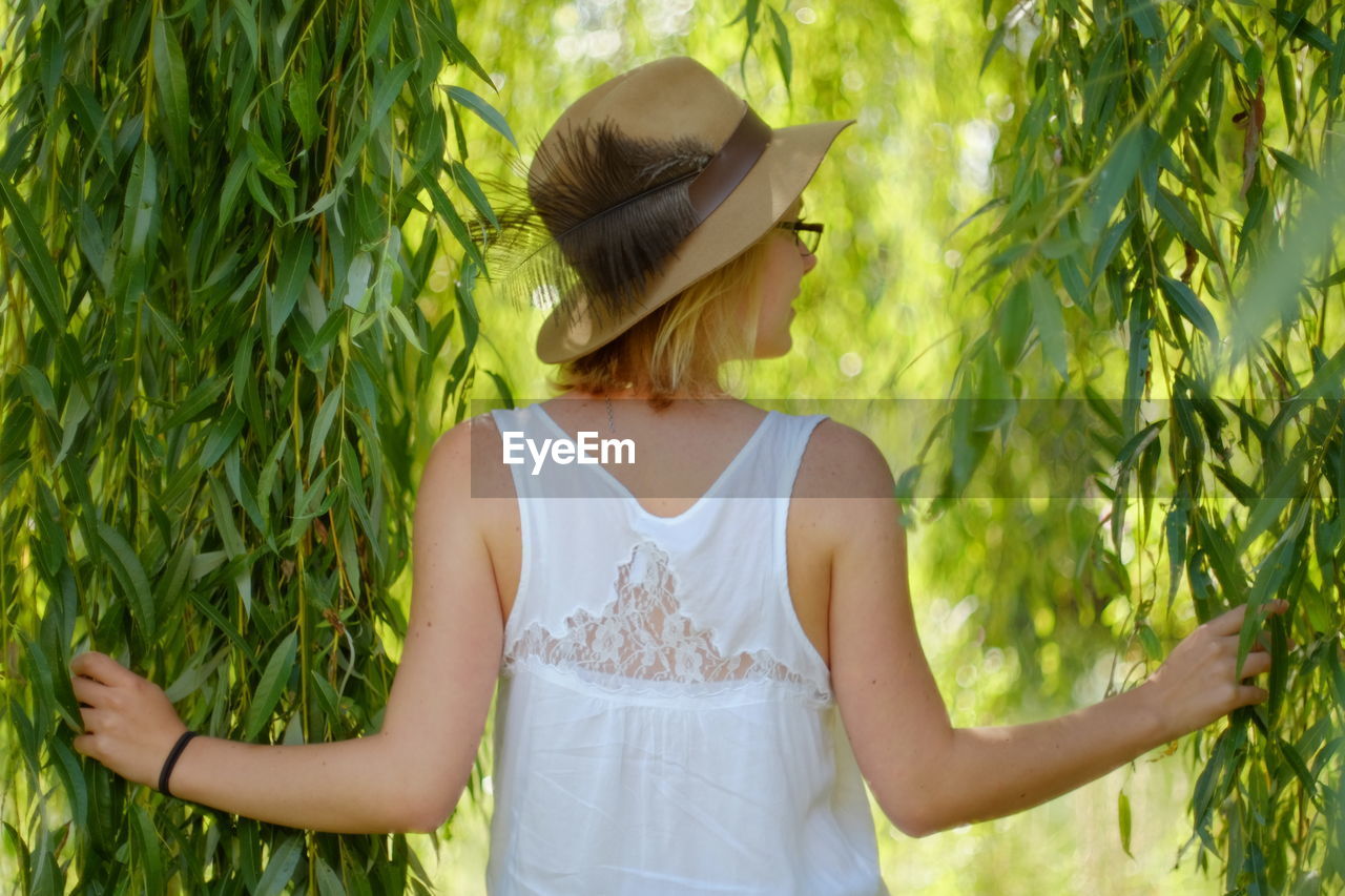 Rear view of young woman holding leaves