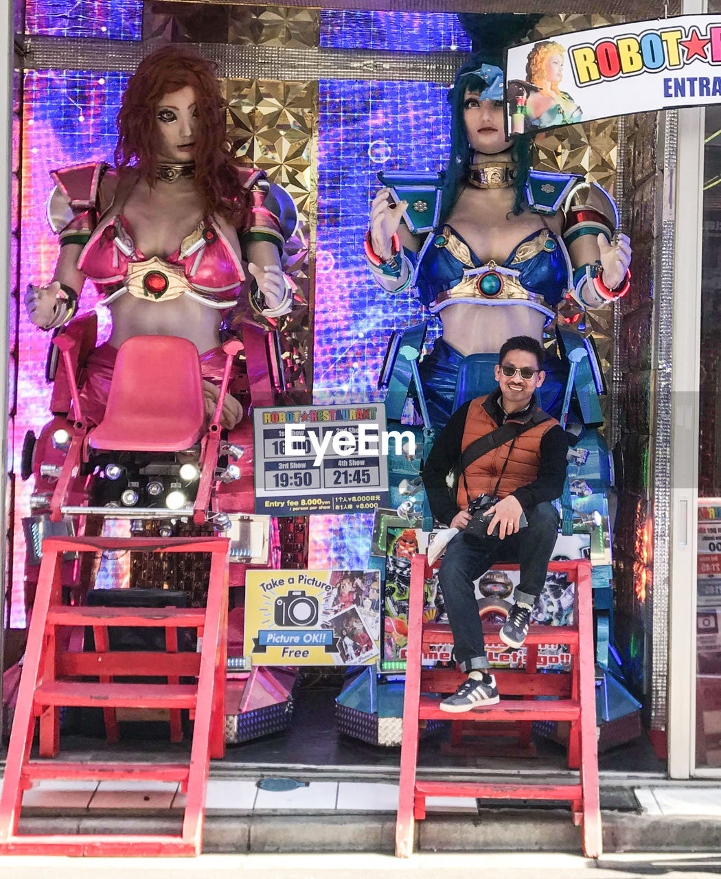 FULL LENGTH PORTRAIT OF YOUNG WOMAN SITTING ON STORE