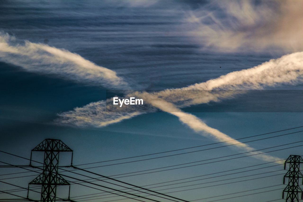 Low angle view of electricity pylon against cloudy sky