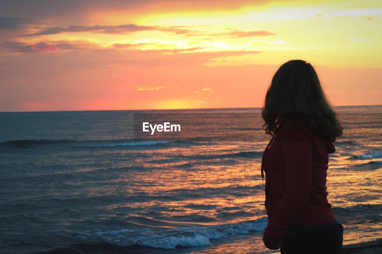 Woman standing at beach during sunset