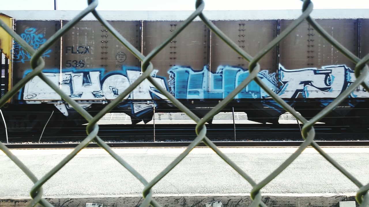 CLOSE-UP OF CHAINLINK FENCE AGAINST CITY