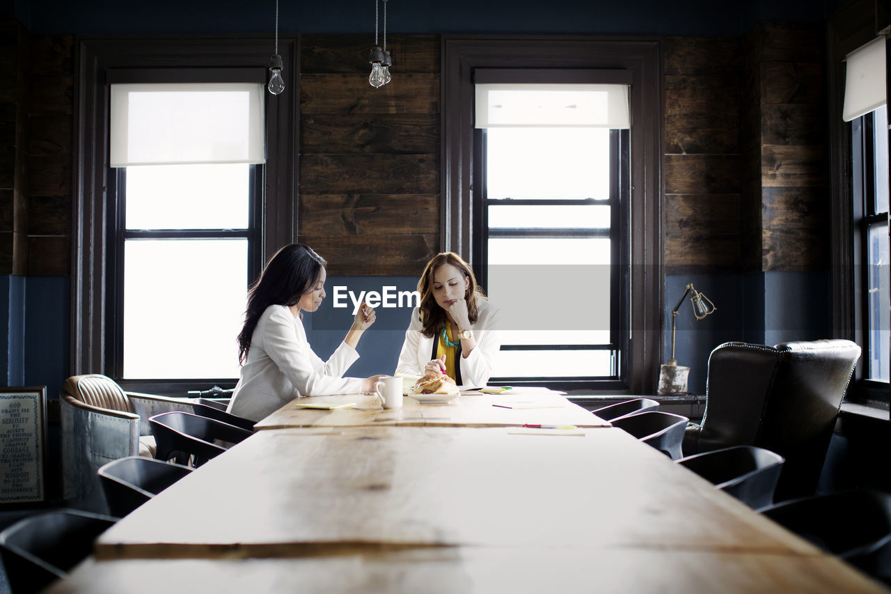 Businesswomen discussing while sitting at desk in office