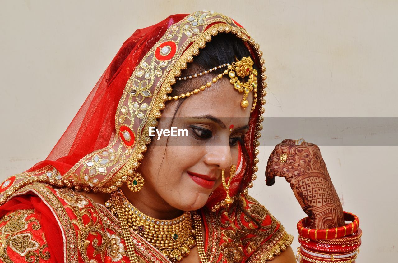 Close-up of bride wearing red sari by wall