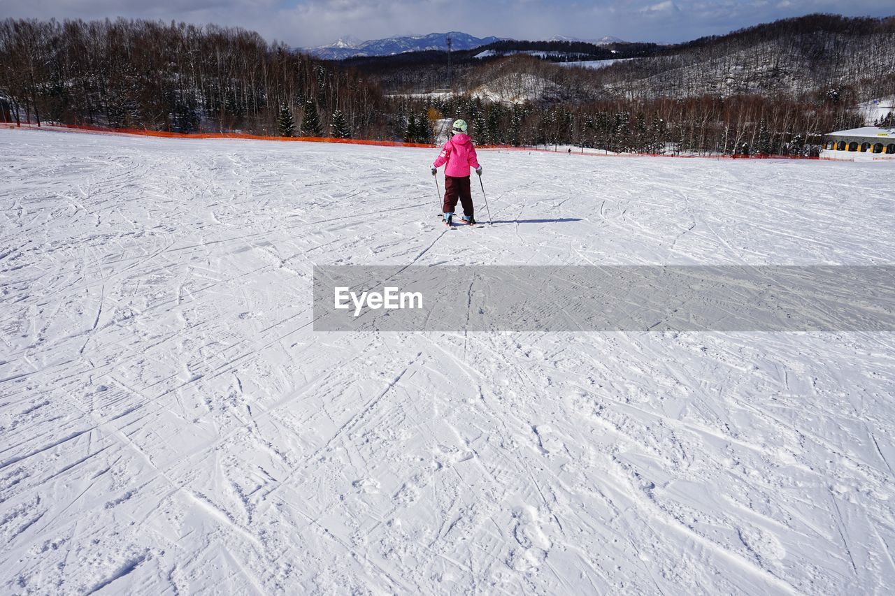 REAR VIEW OF PERSON ON SNOW COVERED FIELD