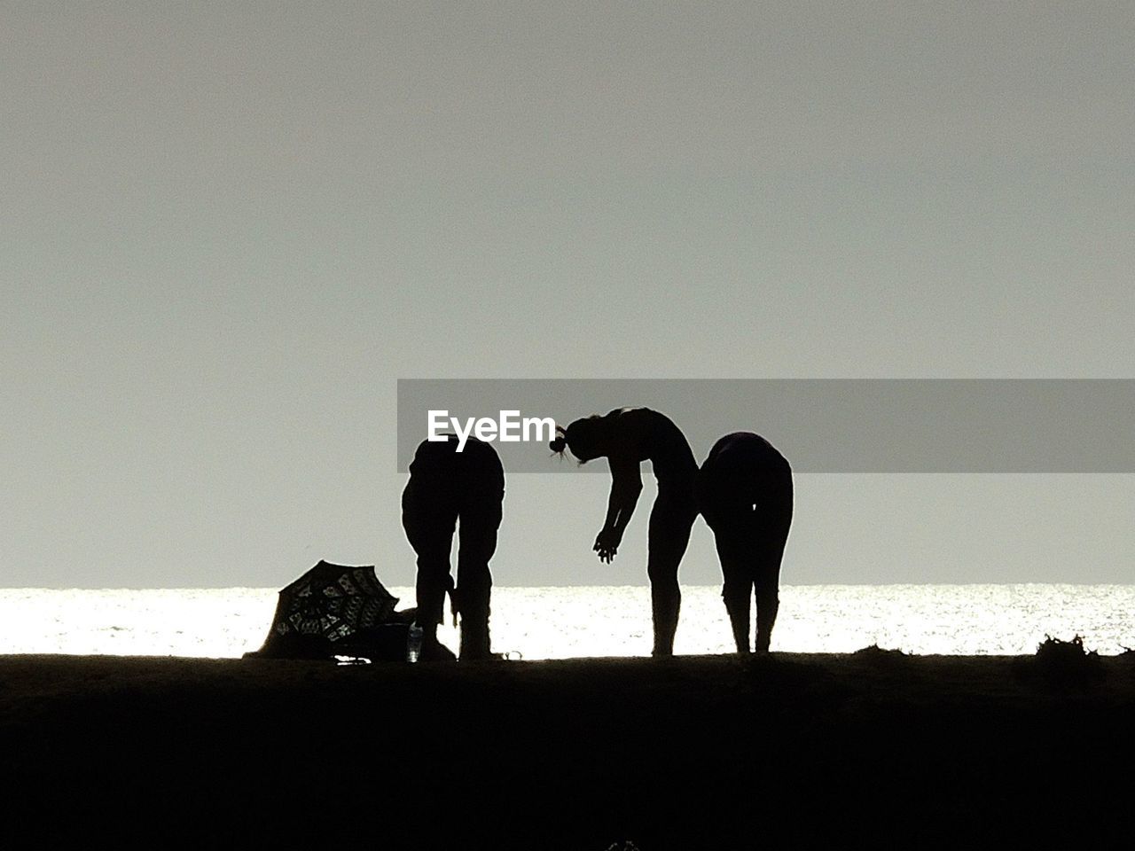 SILHOUETTE PEOPLE STANDING BY SEA AGAINST CLEAR SKY