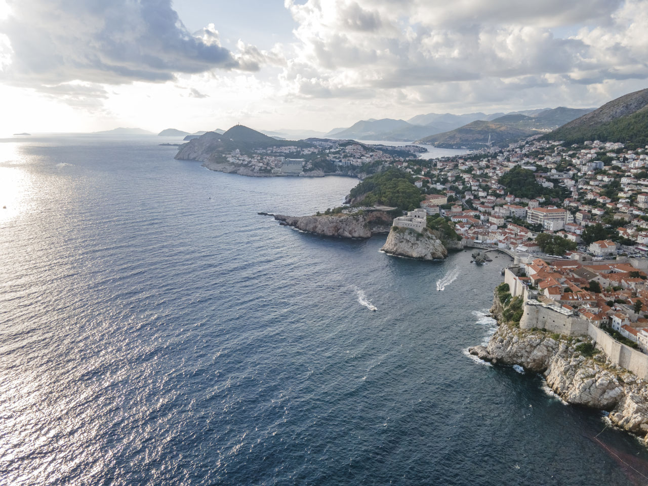 HIGH ANGLE VIEW OF SEA BY MOUNTAINS AGAINST SKY