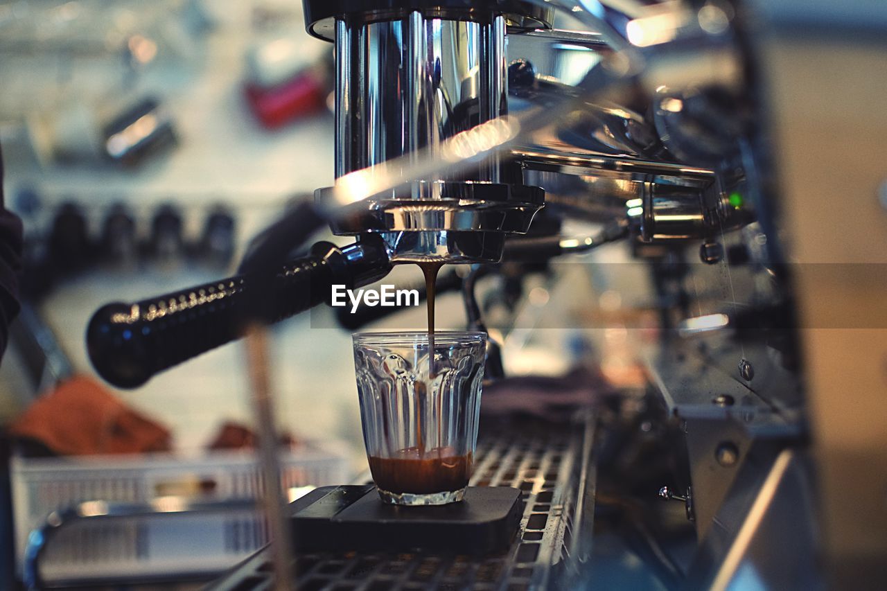 Close-up of espresso maker pouring coffee in cup at cafe