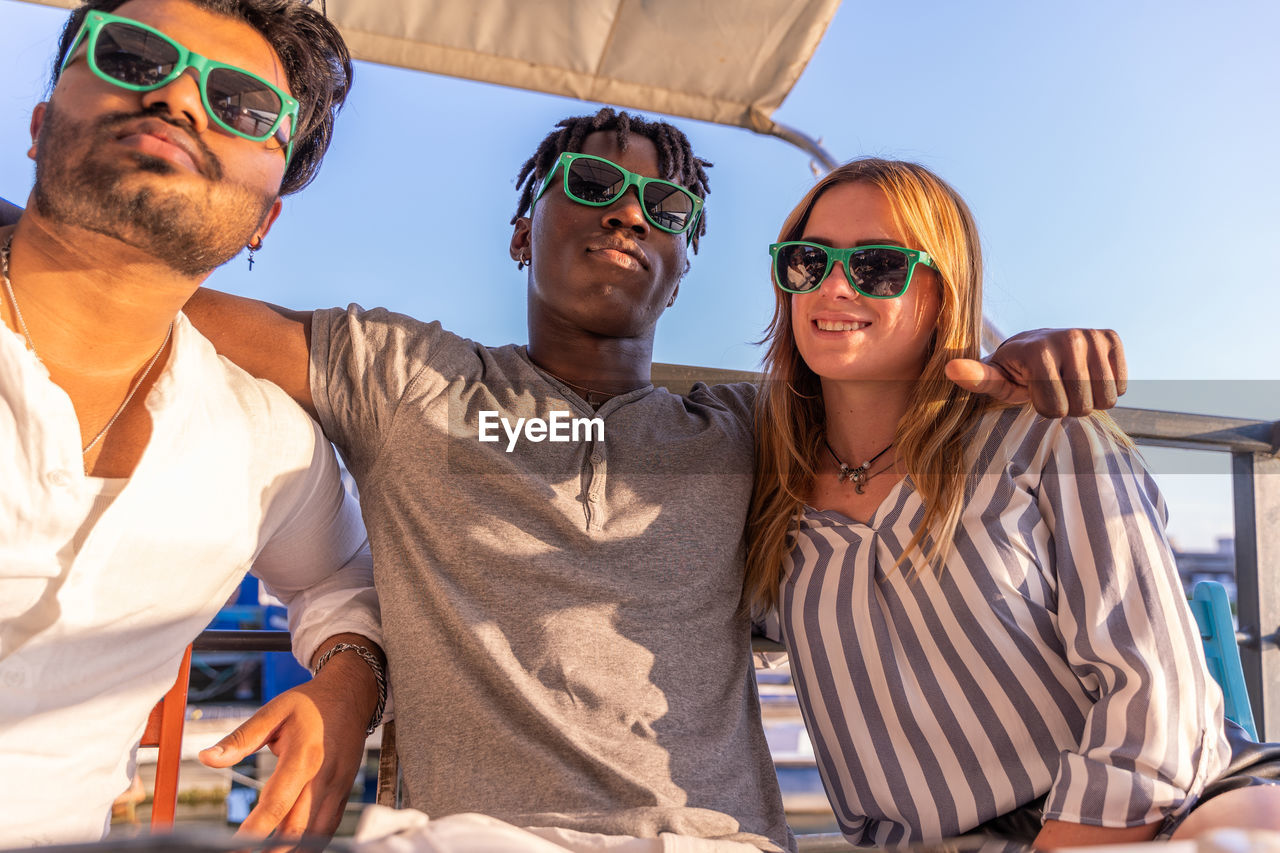 Small group of multiethnic friends having fun wearing green sunglasses on summer vacation concept