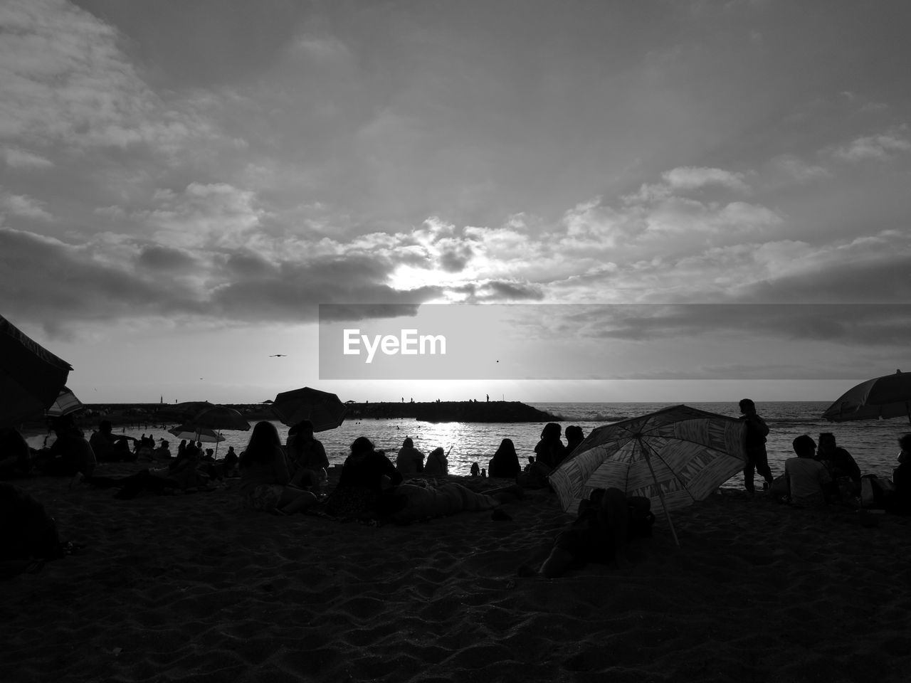 Silhouette people at beach against sky during sunset