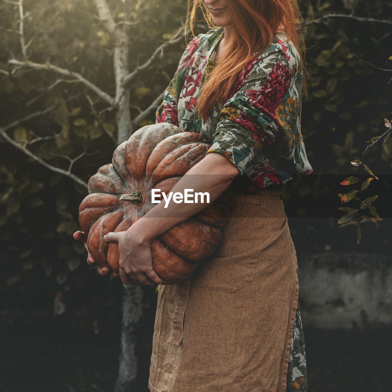 Midsection of woman holding pumpkin while standing outdoors
