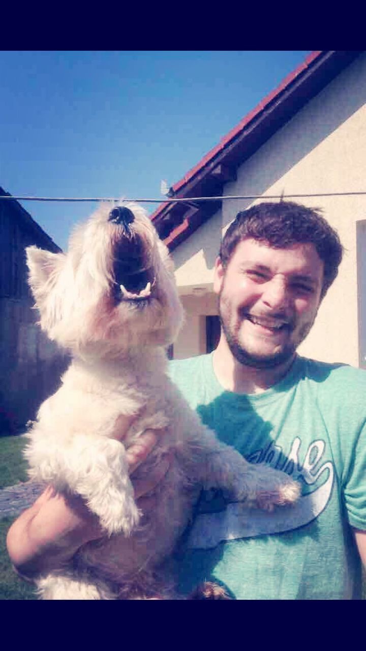 PORTRAIT OF SMILING MAN WITH DOG AT HOME