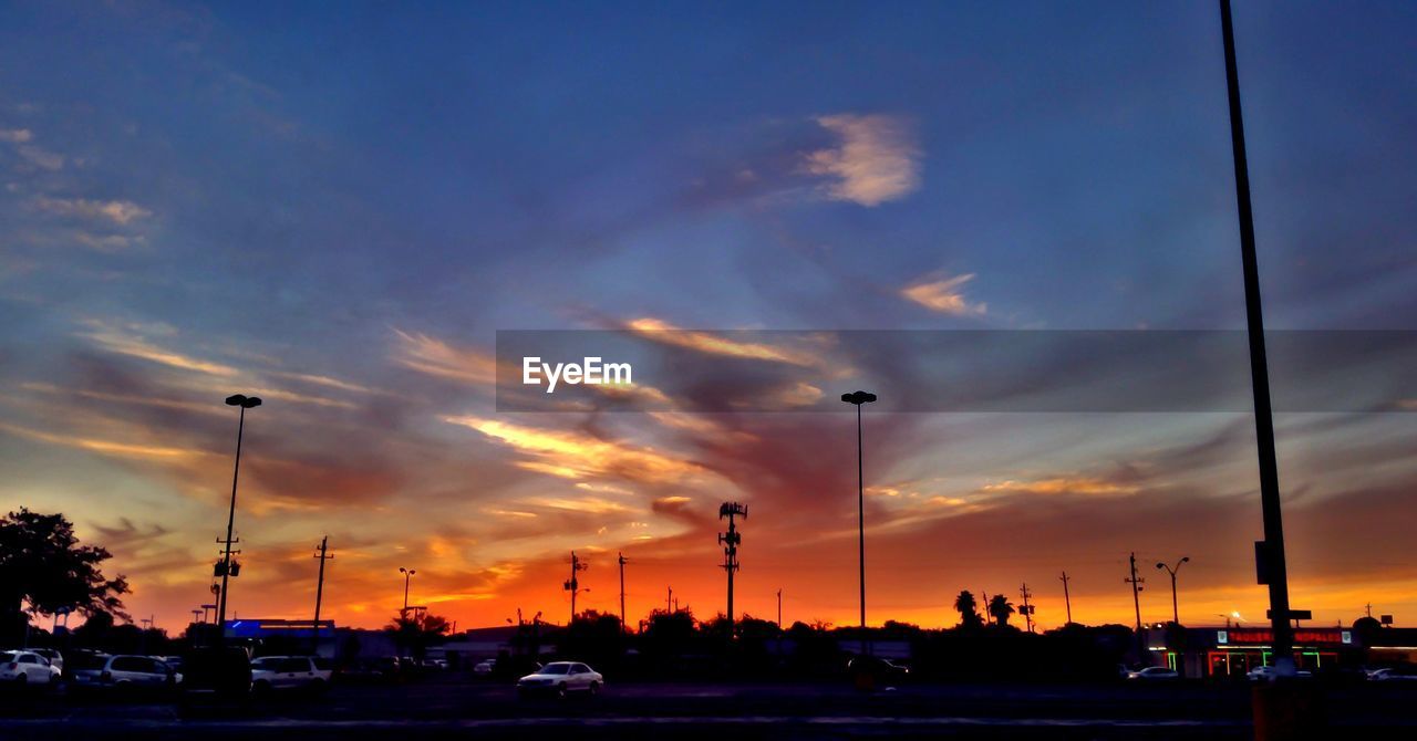 SILHOUETTE CARS ON ROAD AGAINST SKY AT SUNSET