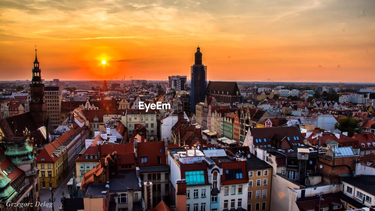 HIGH ANGLE VIEW OF BUILDINGS IN CITY AGAINST SKY DURING SUNSET