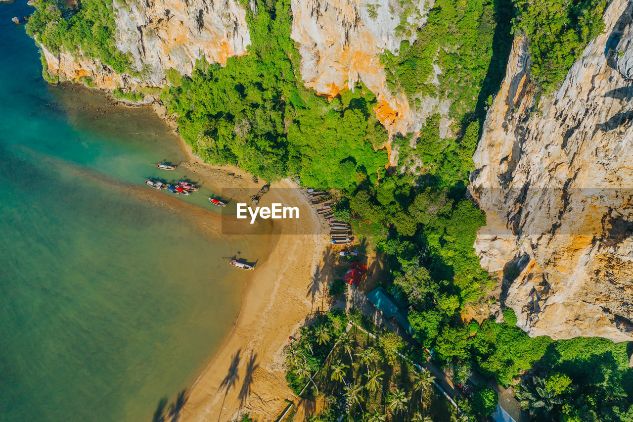 HIGH ANGLE VIEW OF PEOPLE ON ROCK FORMATION AT SEA