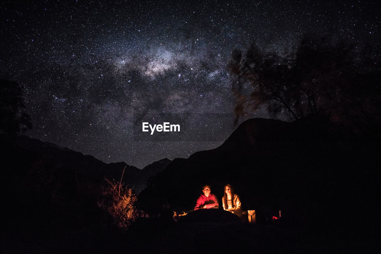 Silhouette people on mountain against sky at night