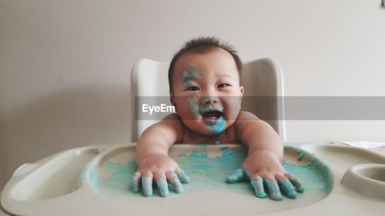 Portrait of baby boy playing with watercolor paints on table