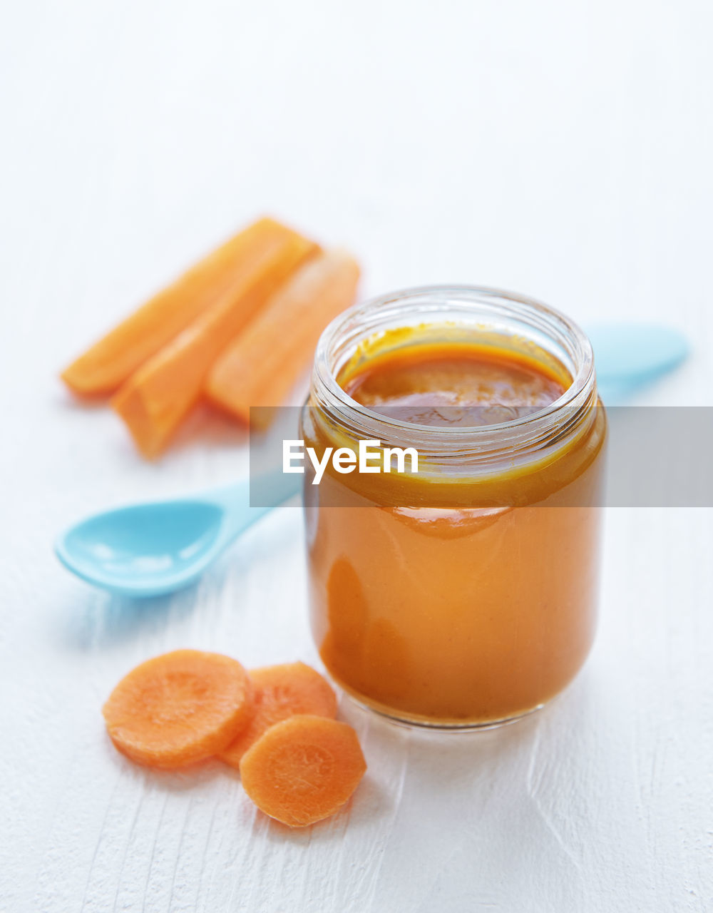 Baby carrot mashed with spoon in glass jar, baby food