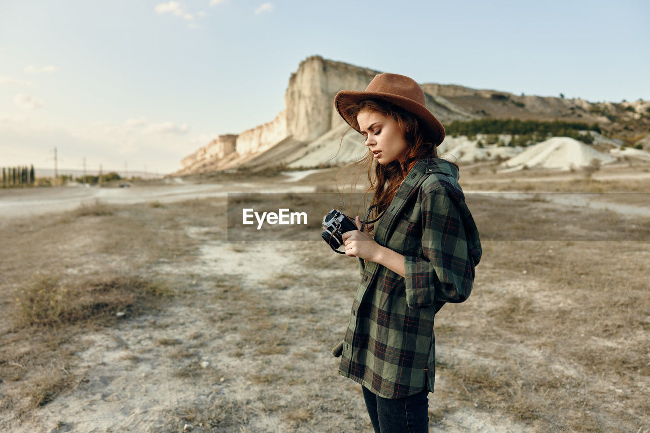 side view of young woman standing against sky