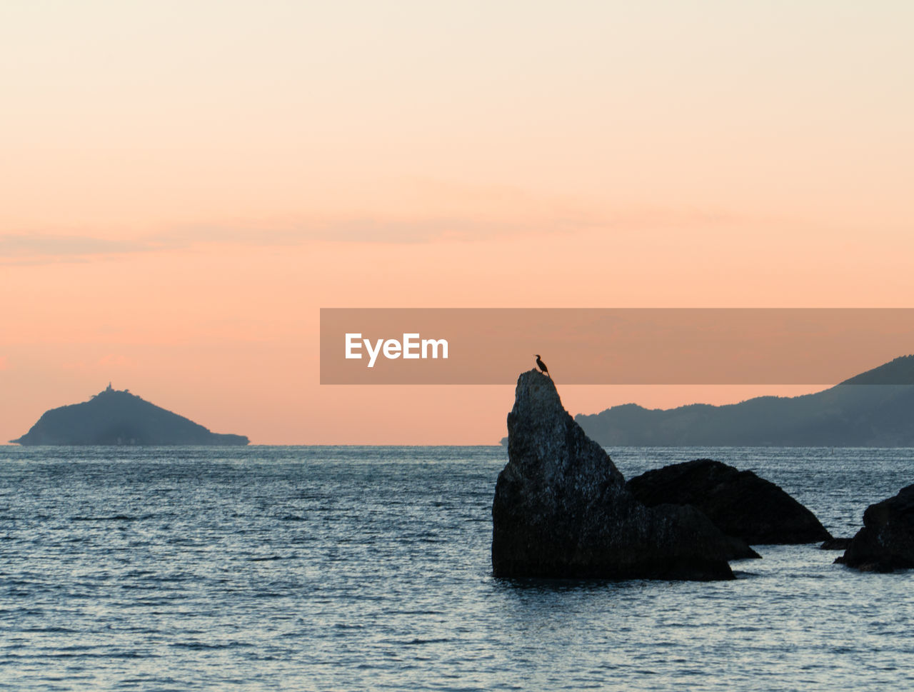 Rocks on sea against sky during sunset