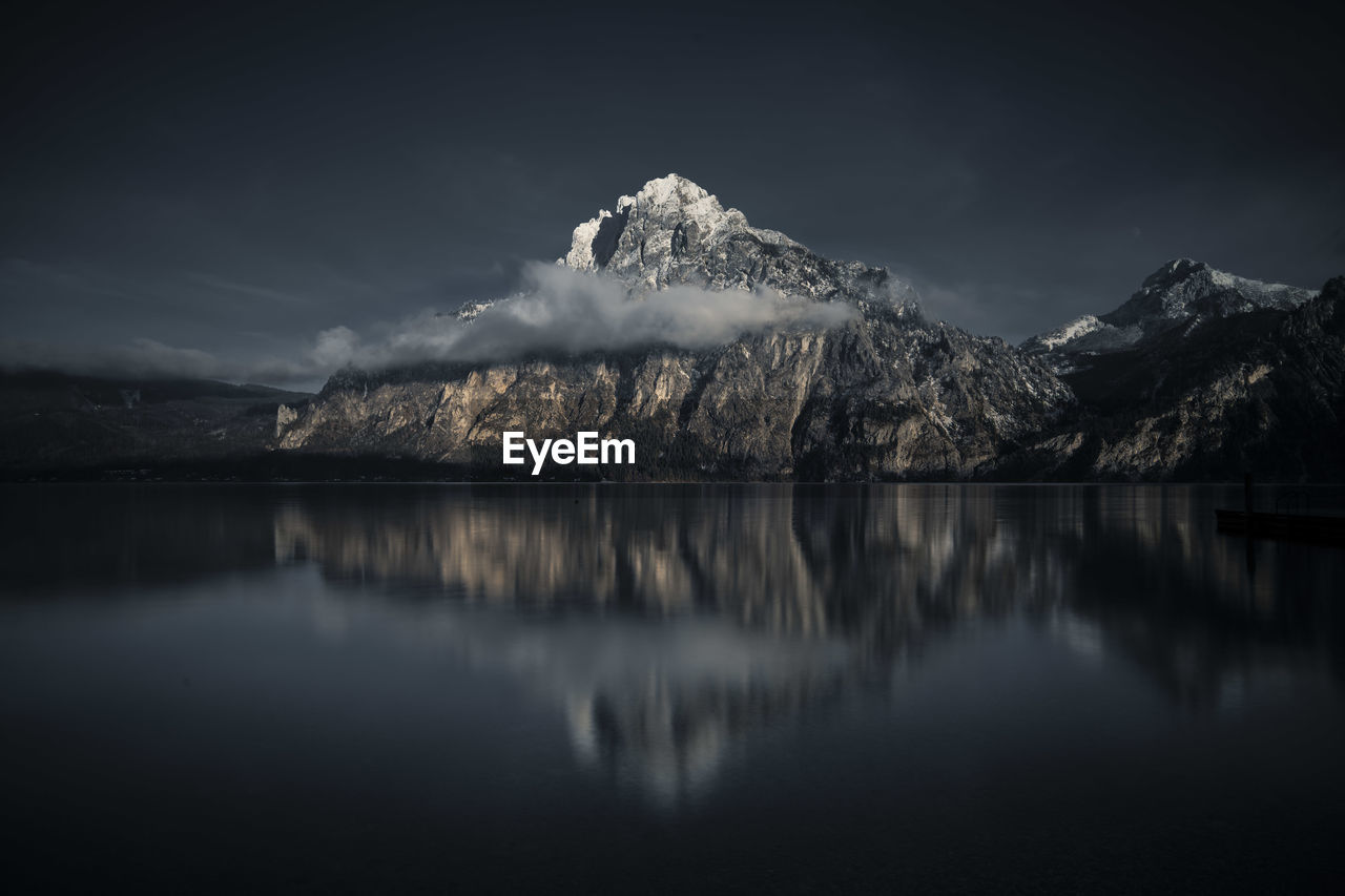 Scenic view of lake by snowcapped mountains against sky