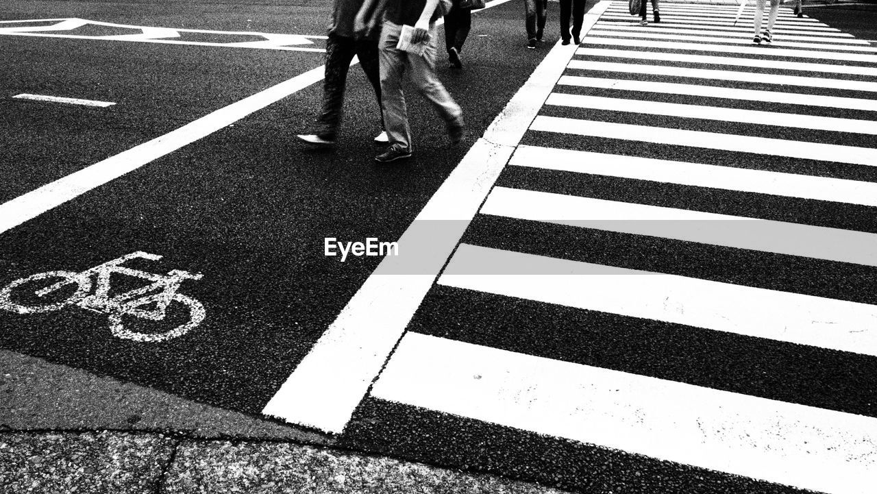 Low section of people walking on zebra crossing