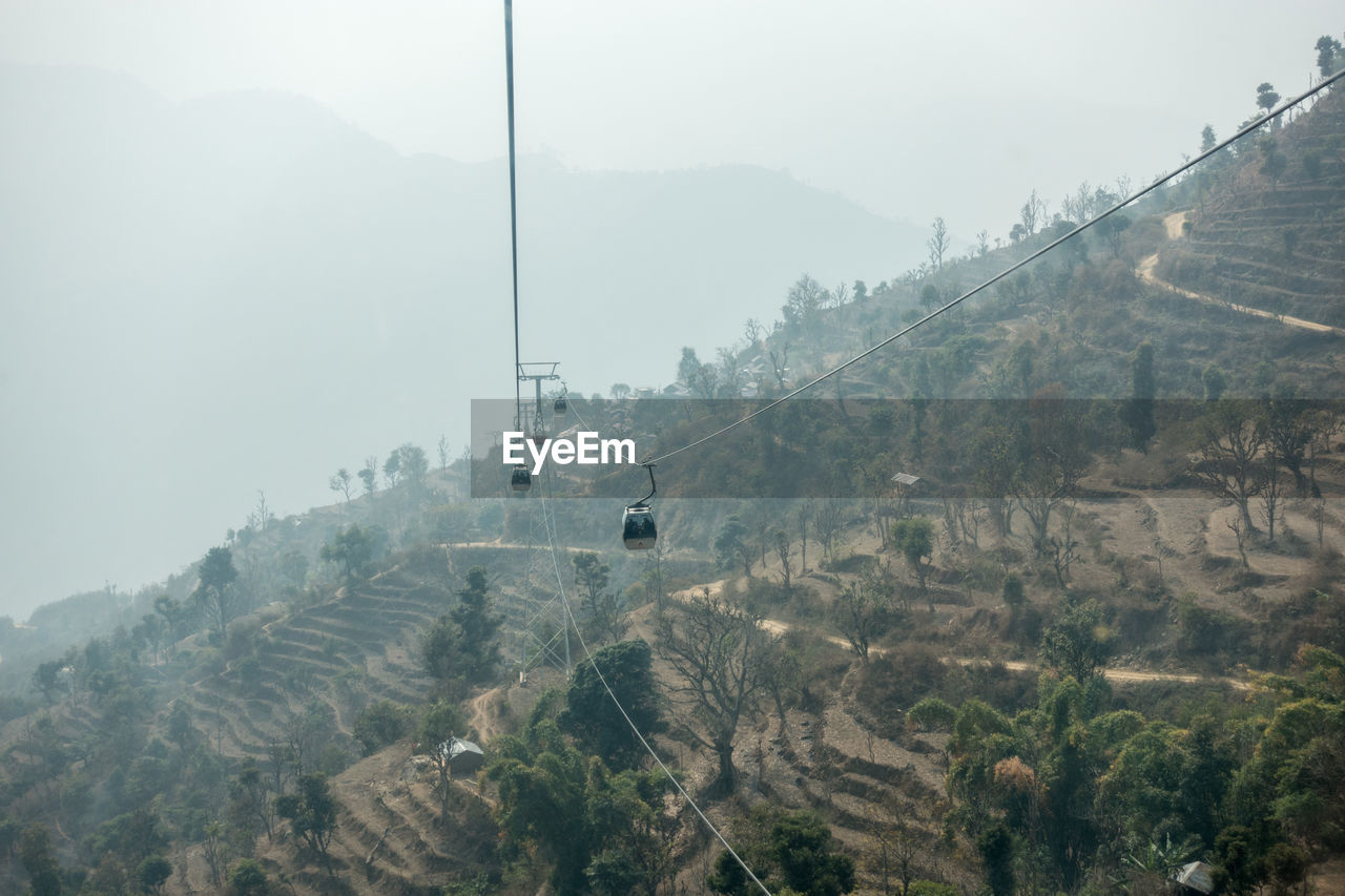 Overhead cable car over mountains against sky