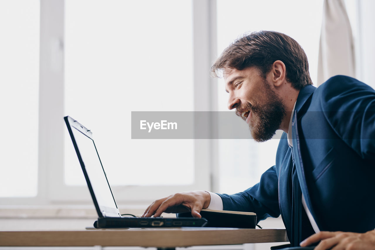 Side view of man using laptop at home