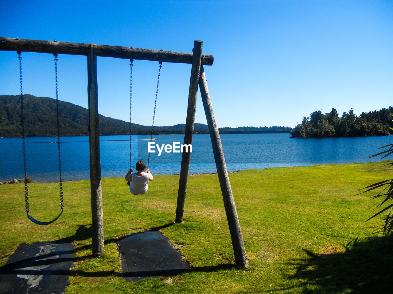 Rear view of baby swinging on swing against clear sky