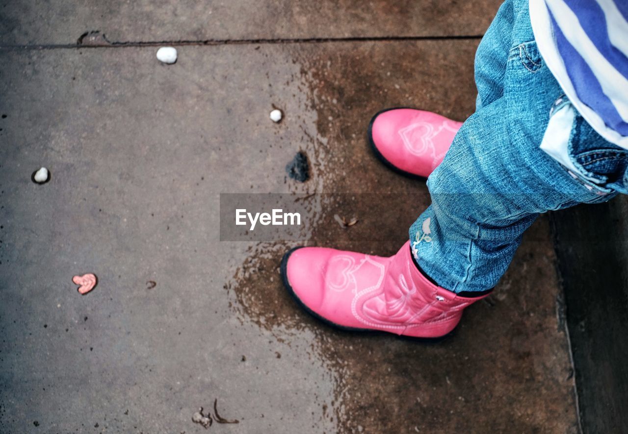 Low section of girl standing on wet pavement