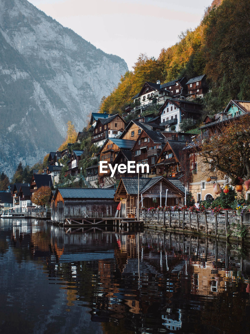 Houses by lake and buildings against sky