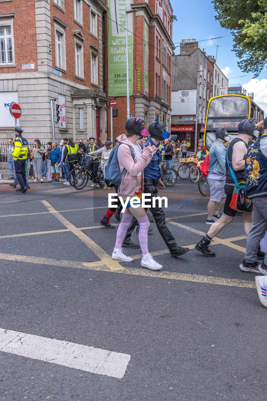 city, architecture, street, group of people, building exterior, built structure, men, road, transportation, day, sign, city street, person, city life, adult, full length, women, festival, clothing, road marking, walking, crowd, large group of people, occupation, outdoors, lifestyles, long distance running